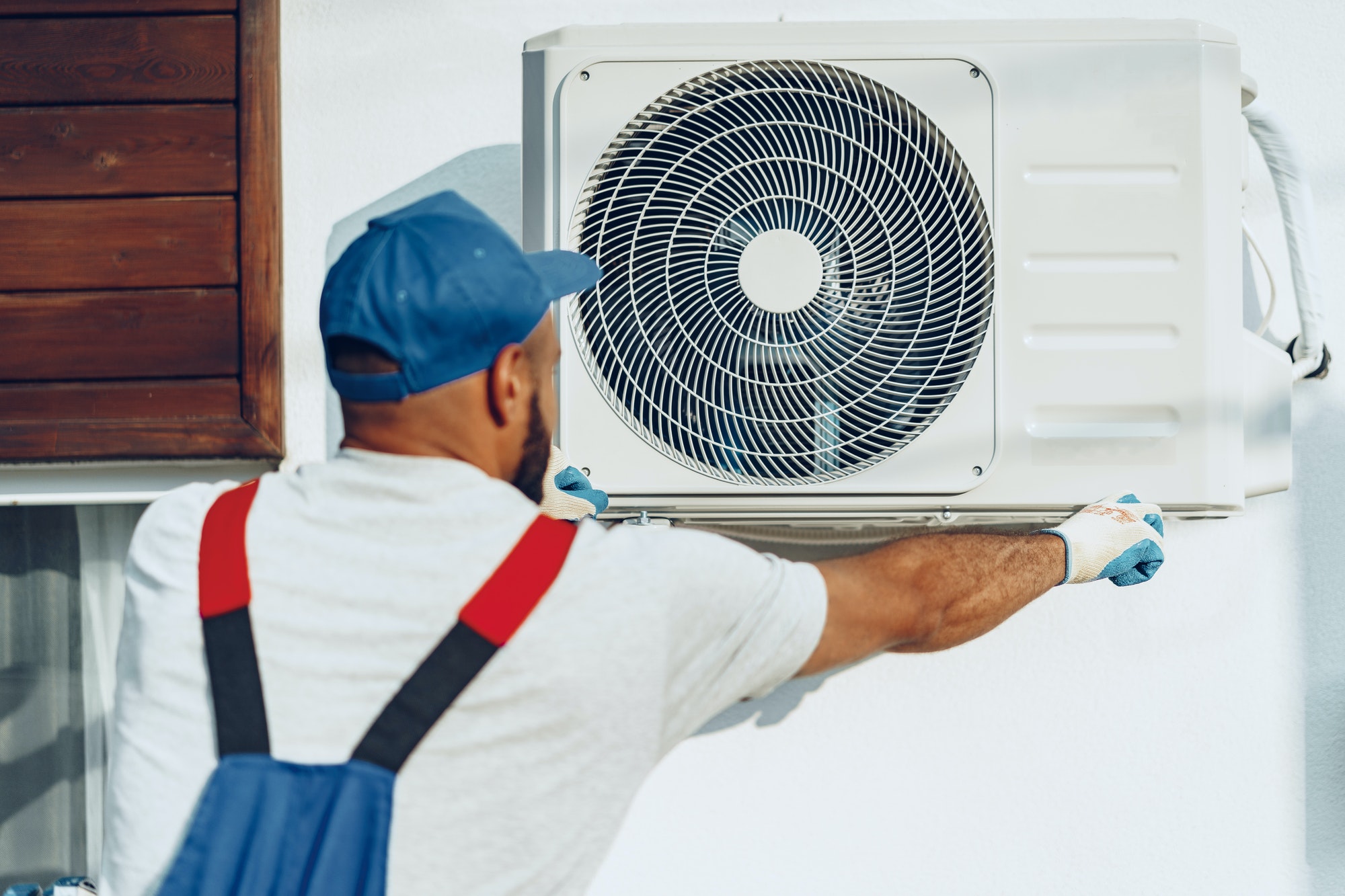 Repairman in uniform installing the outside unit of air conditioner